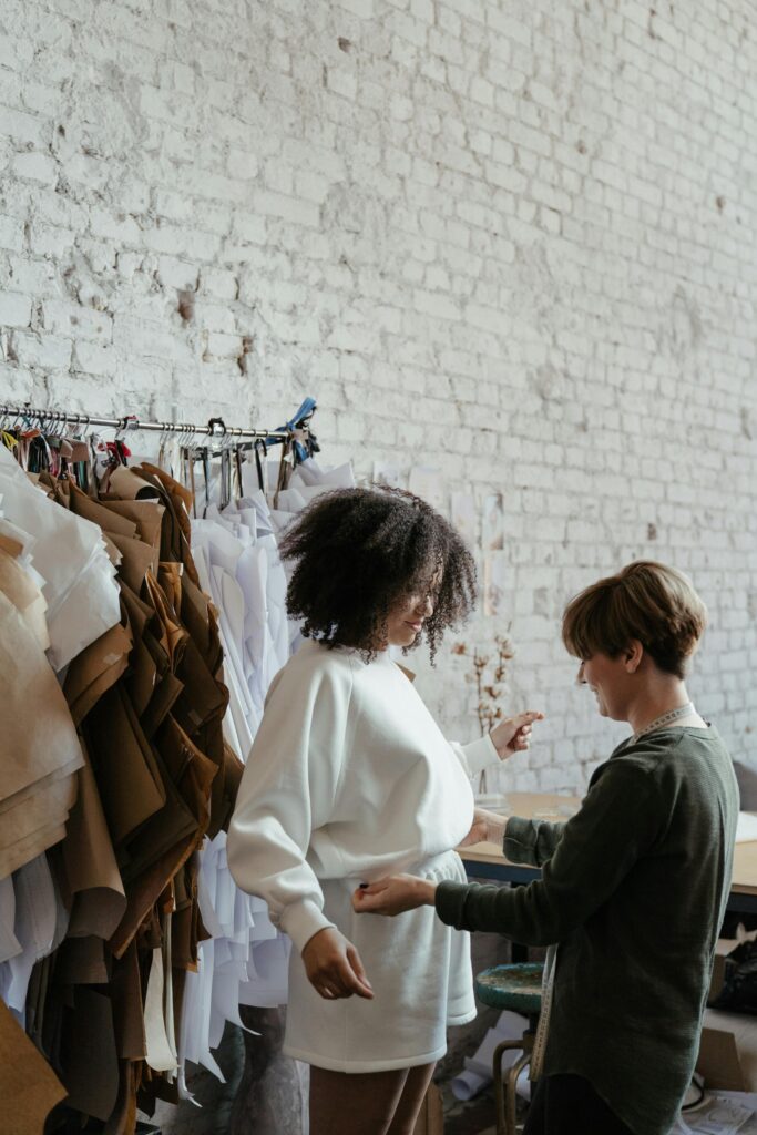 Fashion designer adjusts garment on model in a stylish studio setting.